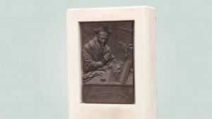 Bronzen plaquette cornelius a lapide, zijaanzicht in witte omlijsting van beton