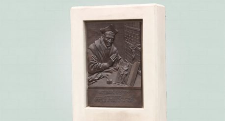 Bronzen plaquette cornelius a lapide, zijaanzicht in witte omlijsting van beton