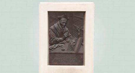 Bronzen plaquette cornelius a lapide, zijaanzicht in witte omlijsting van beton, rechts